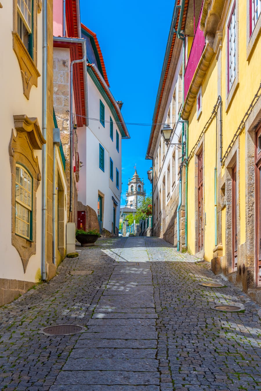 Een smal straatje in de Alta van Viseu met witte huizen en een fontein
